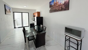 A modern kitchen with a refrigerator, microwave, and a dining area with a glass table and chairs. - Residencia Gran Coyula Orange 510A (Tonala)
