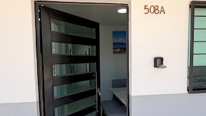 A door with a black frame and glass panels, a number '508A' on the wall, and a small window with a view of a building. - Residencia Gran Coyula Orange 508A (Tonala)