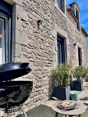 A stone building with a grill and potted plants outside. - Charming house with harbor and ocean views—garden and beaches within walking distance | Lesconil⁠ (Plobannalec-Lesconil)