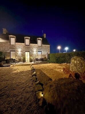 A stone building with a well-lit entrance and outdoor seating area. - Charming house with harbor and ocean views—garden and beaches within walking distance | Lesconil⁠ (Plobannalec-Lesconil)
