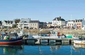 A harbor with boats docked, buildings with commercial establishments, and a clear sky. - Charming House with Views of the Harbor and Ocean - Garden & Beaches Within Walking Distance | Lesconil⁠ (Plobannalec-Lesconil)