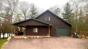 Una baita di legno con un garage, un portico coperto e una scultura di un orso.