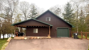 A wooden cabin with a garage, a covered porch, and a bear sculpture. - McCarry Lakehouse 
Peaceful Waterfront Escape (Iron River)