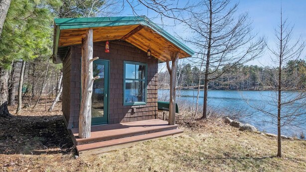 Un piccolo chalet con tetto verde, pareti in legno e un portico.