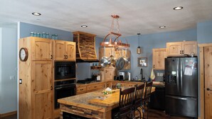 Una cucina con mobili in legno, un frigorifero in acciaio inossidabile e un'isola centrale con sedie.
