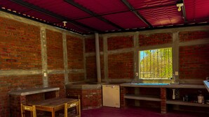 A room with brick walls, a window with a view, a sink, and a small refrigerator. - Casa Mariposa (Santa Maria Huatulco)