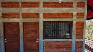 A building facade with two wooden doors, a window with metal bars, and a brick wall. - Casa Mariposa (Santa Maria Huatulco)