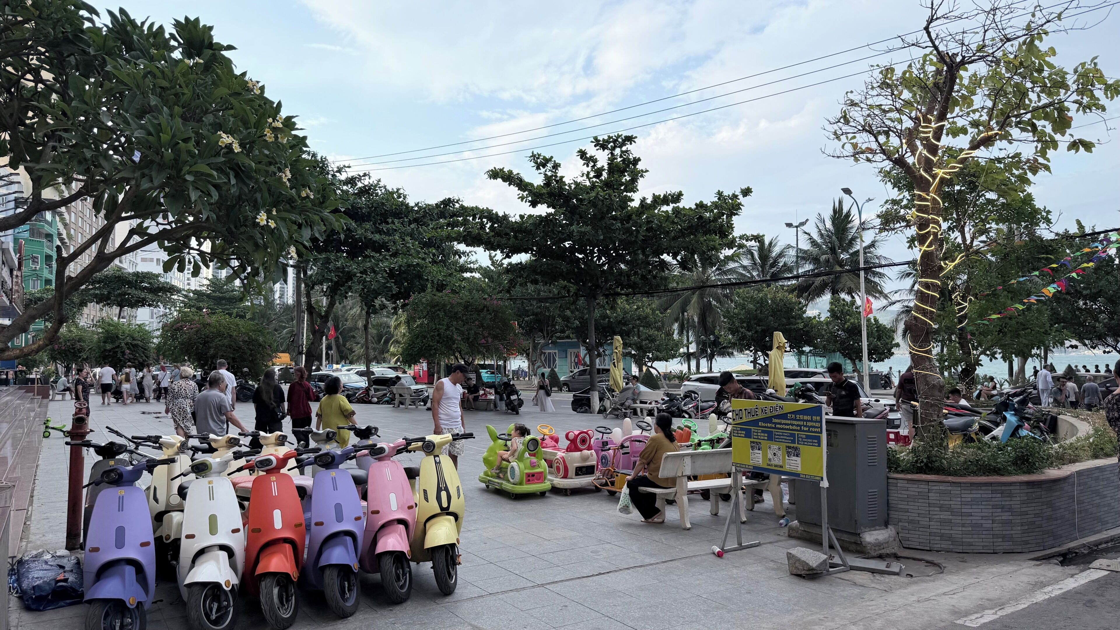A public space with scooters, a signboard, and people.