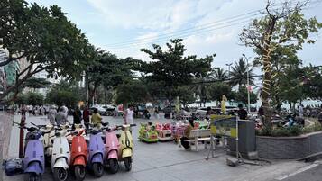 A public space with scooters, a signboard, and people.
