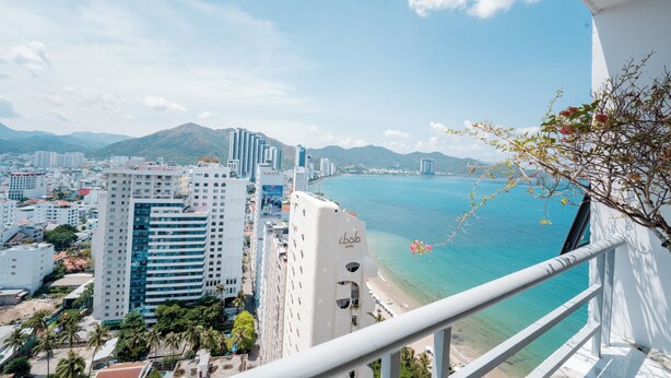 Un hôtel de grande hauteur surplombant une ville côtière, offrant une vue dégagée sur la plage et les montagnes.