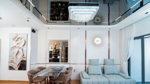 Un salon moderne avec une table à manger en verre, un canapé et un lustre.