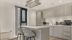Uma cozinha moderna com uma ilha central, banquetas de bar e eletrodomésticos embutidos.