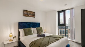 Quarto de hotel moderno com uma cama grande, vista para a cidade e um quadro na parede.