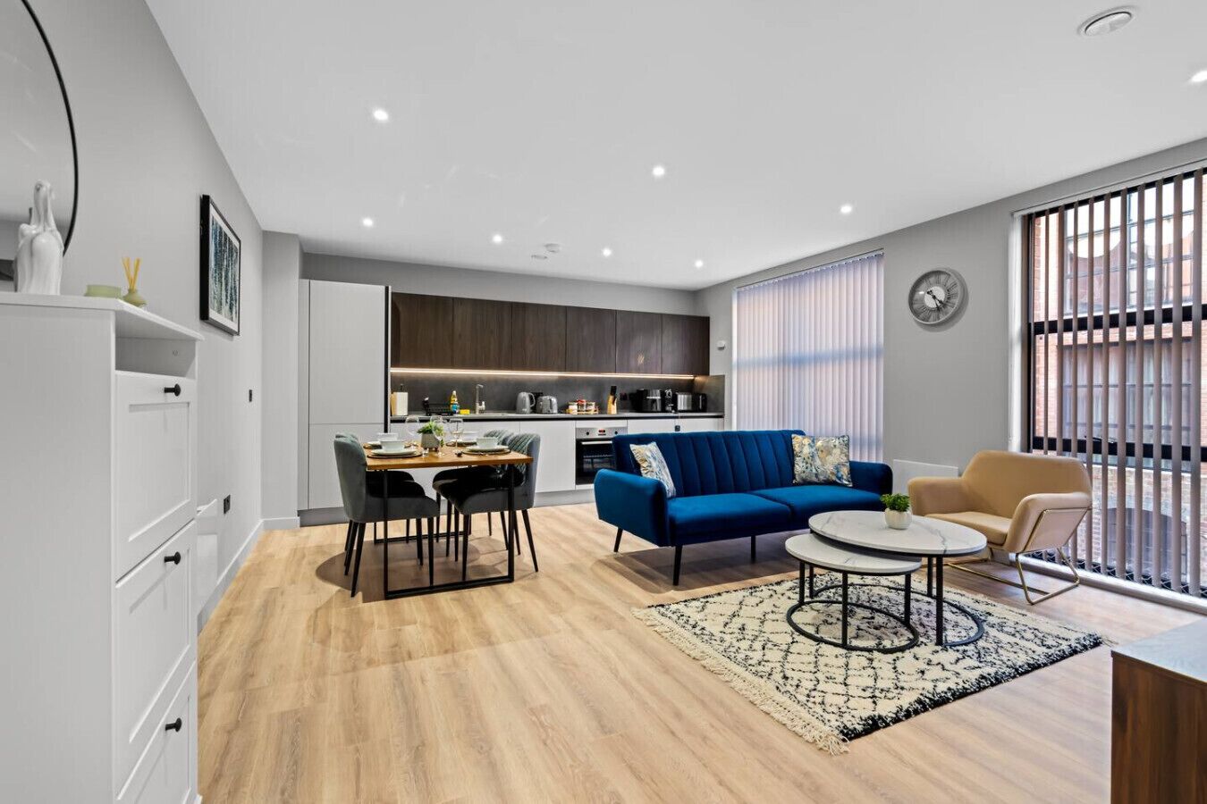 Una sala de estar moderna con comedor, un sofá, una mesa de centro y una cocina al fondo.
