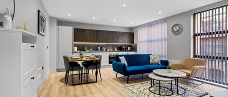 Una sala de estar moderna con comedor, un sofá, una mesa de centro y una cocina al fondo.