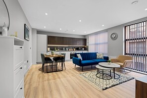 A modern living room with a dining area, a sofa, a coffee table, and a kitchen in the background. - Relax in this luscious comfort | St Paul`s Square (West Midlands)