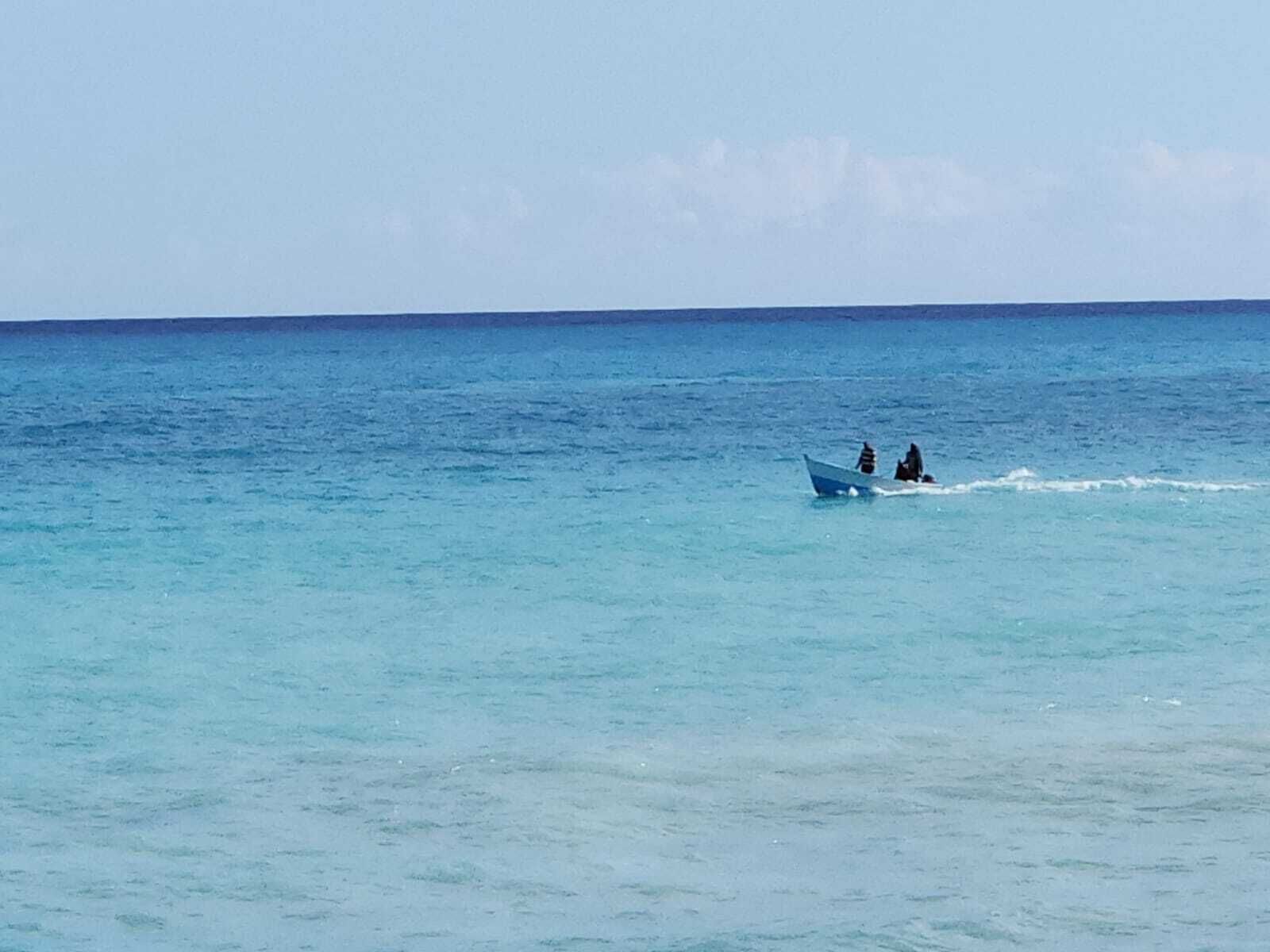 A calm sea with a small boat carrying two people.
