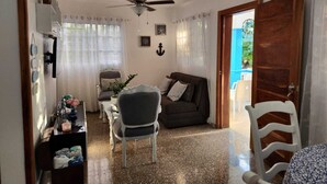 A cozy living room with a ceiling fan, a dining area with a table and chairs, and a door leading to an outdoor area.