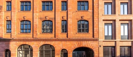 A red brick building with multiple windows and a large arched entrance.