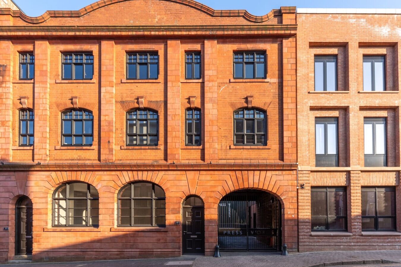 A red brick building with multiple windows and a large arched entrance.