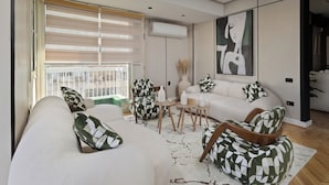 Un salon moderne avec un canapé, des fauteuils, une table basse et un tableau accroché au mur.