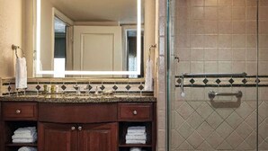 Une salle de bain avec un meuble-lavabo, un miroir, une douche avec une porte en verre et un pare-splash en carrelage.