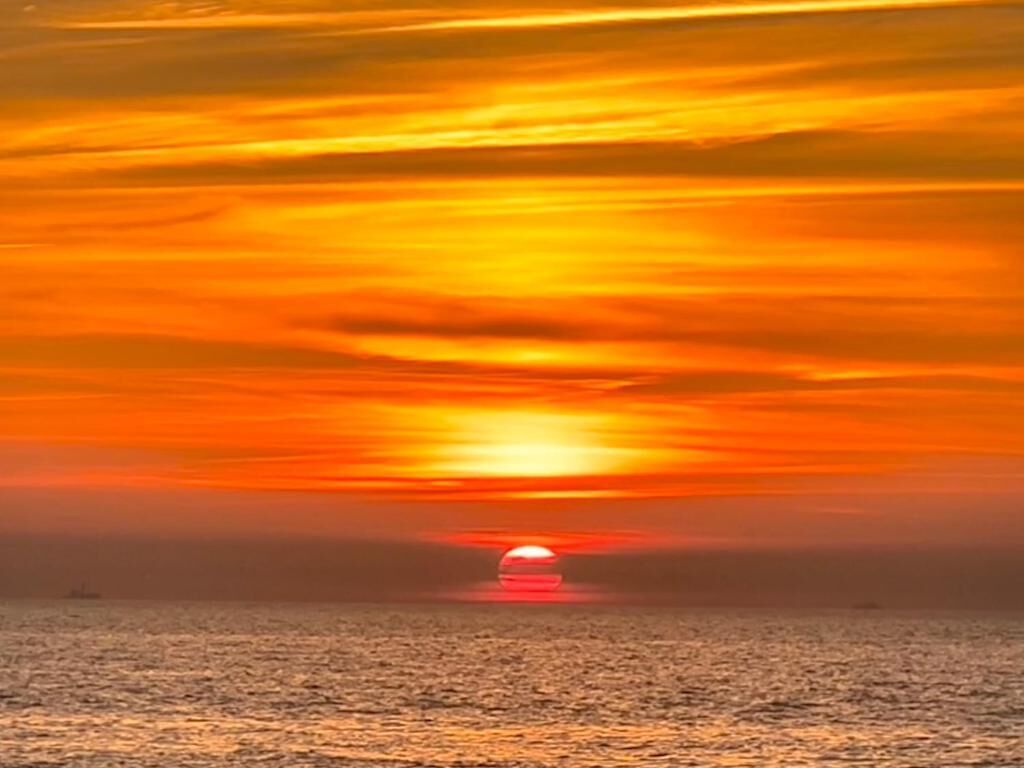 En solnedgång över havet med ett lugnt hav och en klar himmel.