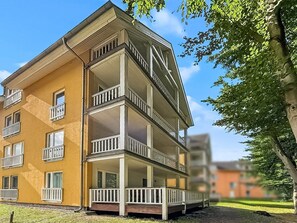 Ein mehrstöckiges Gebäude mit Balkonen und einer flachen Dachterrasse.