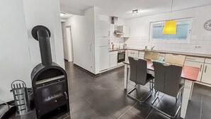 Una cocina moderna con una isla central, estufa y comedor con sillas.