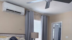 A bedroom with a bed, a ceiling fan, an air conditioning unit, a lamp, and a door. - Adorable 1-bedroom apartment within 5 minute walk to UF Healthand Proton (Jacksonville)