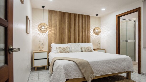 Ein Schlafzimmer mit Bett, Nachttischen, einem Holzkopfende und einer Tür.