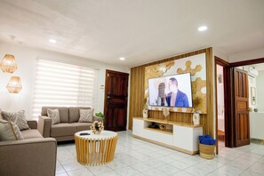 A living room with a sofa, TV, and a round coffee table. - Welcoming 4-bedroom house with AC in vibrant Jacó (Jacó)