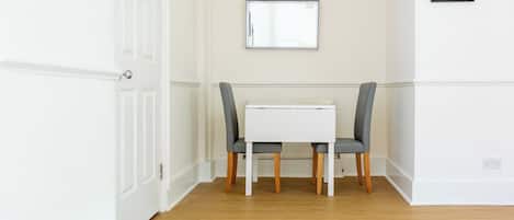 A room with a white door, a white table with two chairs, and a framed map on the wall.