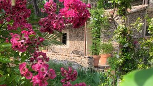 Un edificio in pietra con un giardino antistante, immerso nel verde.