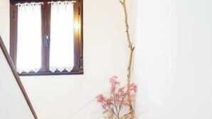 Uma escadaria de mármore com um vaso de flores secas no patamar.