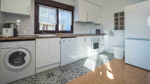 Uma cozinha compacta com máquina de lavar, micro-ondas e frigorífico.