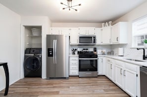 A modern kitchen with white cabinets, stainless steel appliances, and a built-in oven. - Modern Luxury Retreat 3BR/2.5 bath, 2 Decks, Near Christiana & Wilmington (New Castle)