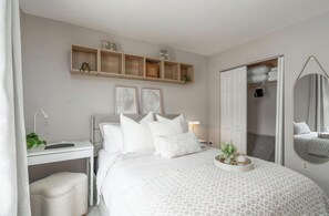 Une chambre à coucher comprenant un lit, une table de chevet, un bureau et une armoire.