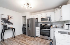 A modern kitchen with stainless steel appliances, white cabinetry, and a black countertop. - Modern Luxury Retreat 3BR/2.5 bath, 2 Decks, Near Christiana & Wilmington (New Castle)