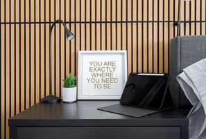 Un bureau bien rangé, agrémenté d’une citation inspirante encadrée, d’une plante en pot, d’une tablette et d’une lampe, le tout adossé à un mur fait de lattes de bois.