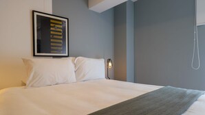 A neatly made bed with white linens, a gray throw blanket, and a framed picture on the wall. - w* | Central 2BR w/ Balcony in Miraflores (Miraflores)