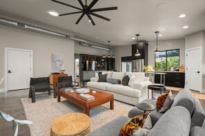 A modern living room with a sofa, coffee table, and a dining area.