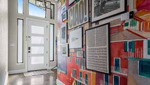 Ein Flur mit einer modernen Tür, einer Wand mit farbenfroher Kunst und einem Sicherheitstastenfeld.