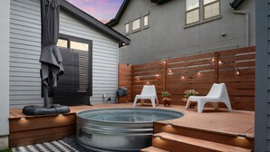 Ein Garten mit Whirlpool, Holzterrasse und Gartenmöbeln.