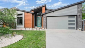 Ein modernes, zweistöckiges Haus mit Garage, Eingangstür und gepflegtem Rasen.