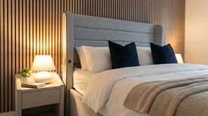 A modern hotel room with a bed, a nightstand, a lamp, and a wall with vertical wooden slats. - Stylish 1-bedroom stay in Dagenham with easy London access (Dagenham)