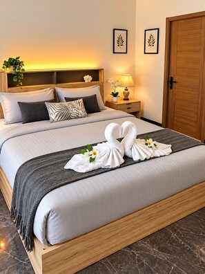 A neatly made bed with a towel arrangement and a nightstand with a lamp. - 1-bedroom ,
own bathroom and shared kitchen in adorable Kata Phuket with AC (Muaeng Phuket)