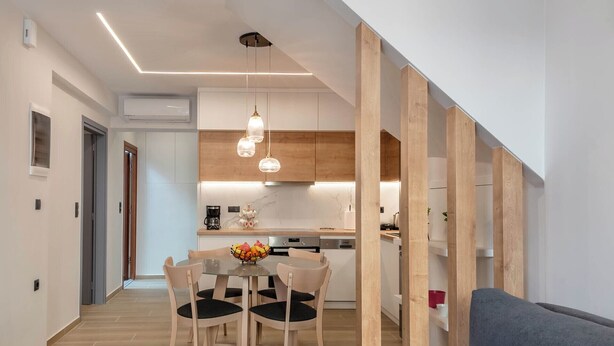Eine moderne Küche mit Holzausbau, ein Essbereich mit Glastisch und Stühlen sowie eine Treppe mit Holzwangen.