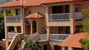 Un edificio de varios pisos con techo de tejas, balcones y una escalera que lleva a la entrada.