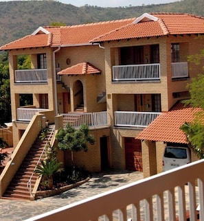 A multi-story building with a tiled roof, balconies, and a staircase leading to the entrance.